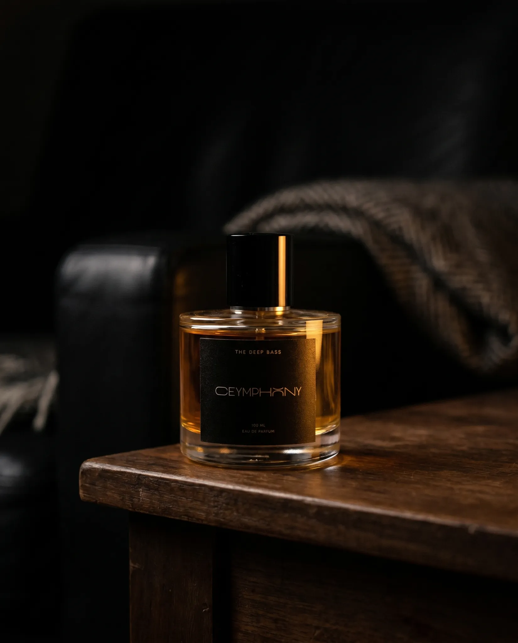 The Deep Bass on a dark walnut side table, amber-lit, a leather armchair and wool throw behind.